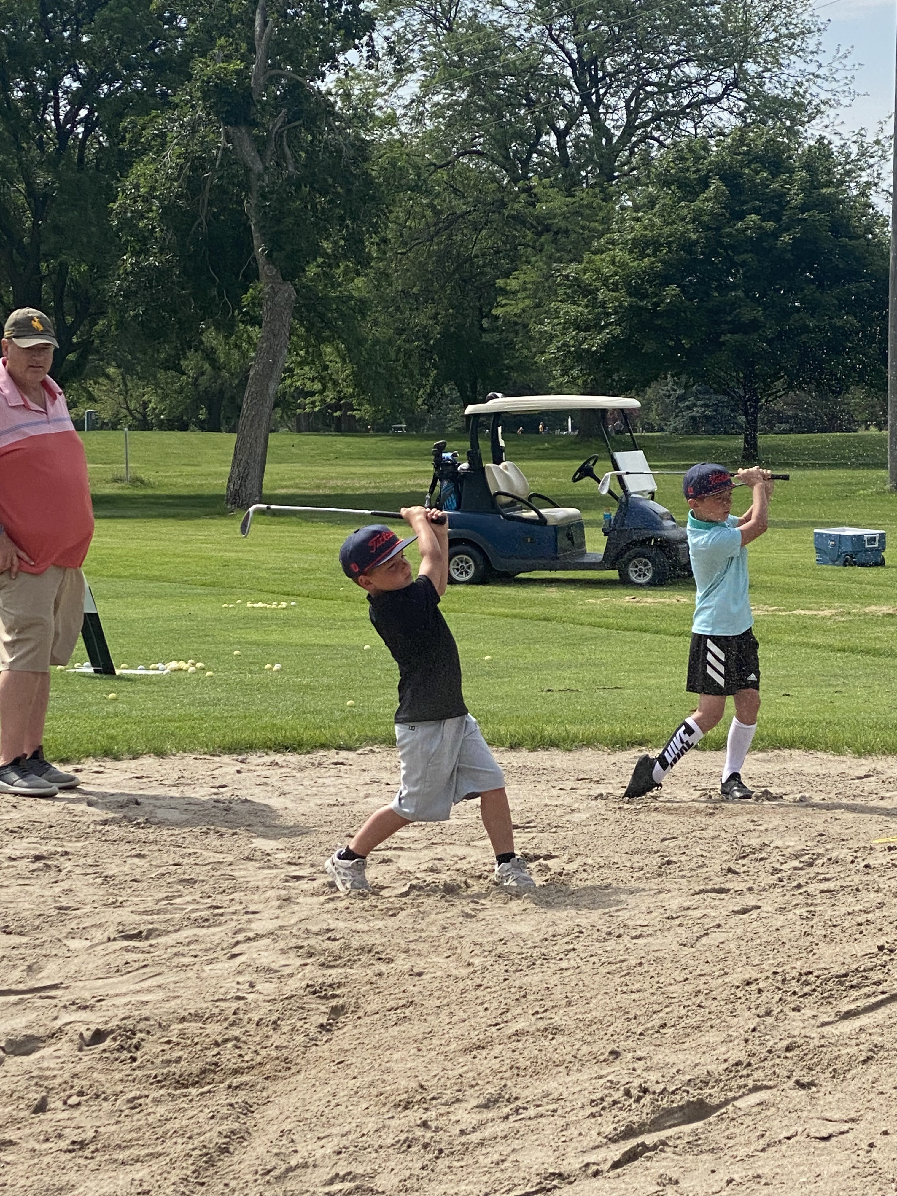 Youth golfers taking a swing on golf course